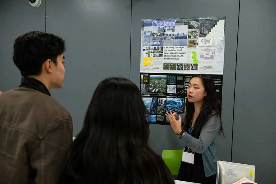 Student making a presentation with two others watching