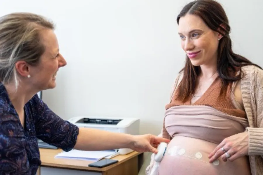 Care provider and a pregnant woman using a wearable monitor.