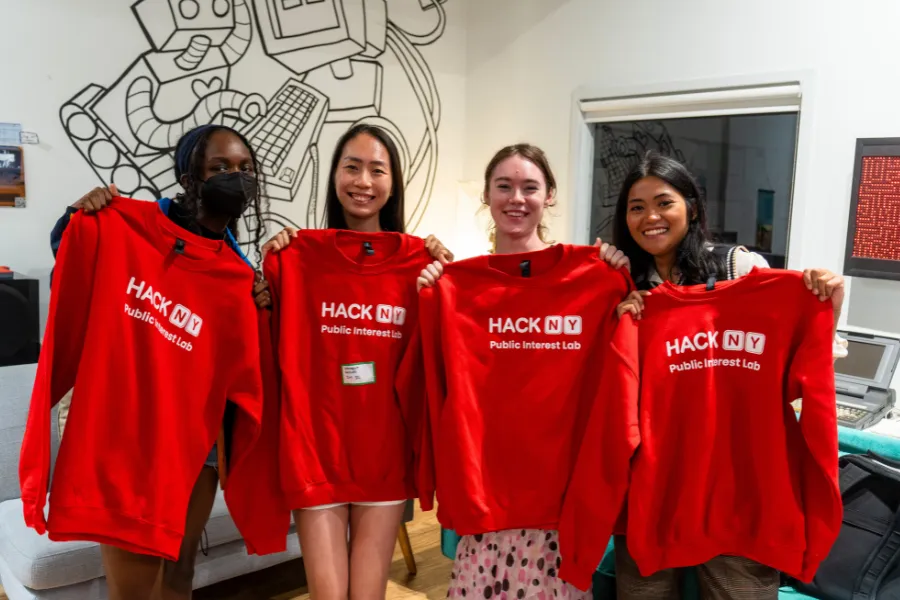 2026 hackNY Fellows Chiazo Agina, Jerica Huang, India Daniel and Jessica Belasoto holding red t-shirts.
