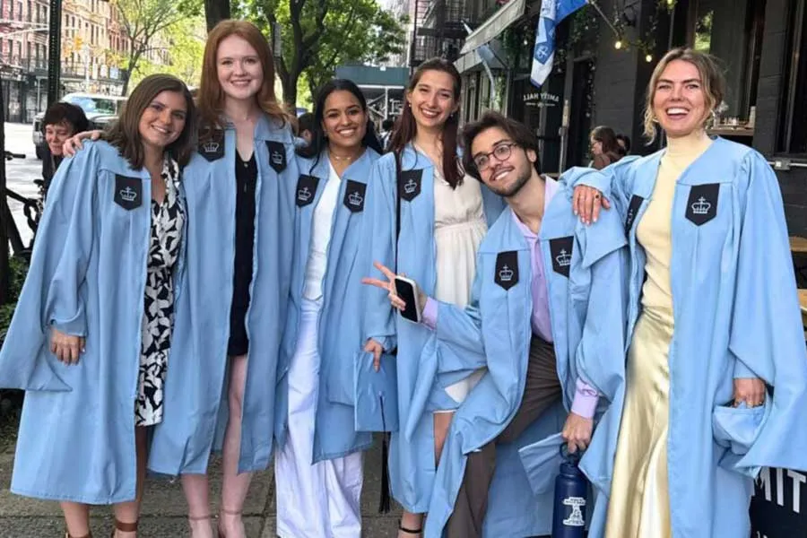 six graduating students in caps and gowns grinning for the camera