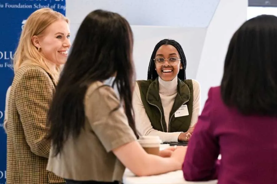 photo of four women standing at a table talking