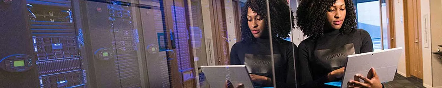female student with a laptop standing in a server room